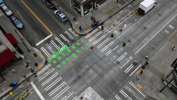 An almost empty intersection in downtown Seattle Washington. An arial shot off of the side of a building that shows the crisscrossing of roads, crosswalks, and bike lanes.