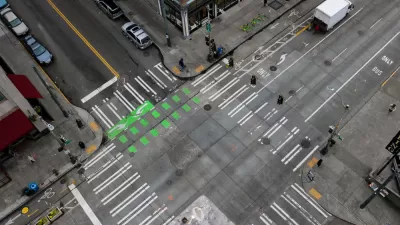An almost empty intersection in downtown Seattle Washington. An arial shot off of the side of a building that shows the crisscrossing of roads, crosswalks, and bike lanes.