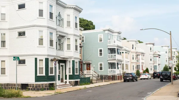 Corner of block with light-colored three-story wooden apartment buildings in Boston, Massachusetts.
