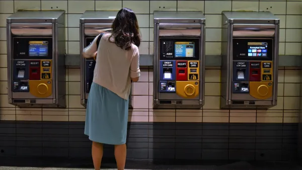 Woman in skirt and sweater using ticketing machine in NYC subway station.