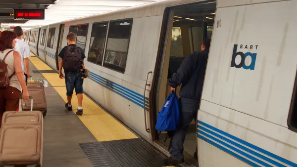 People boarding a white BART train at a platform.
