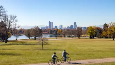 Two bike riders on trail in part with Denver, Colorado skyline in background