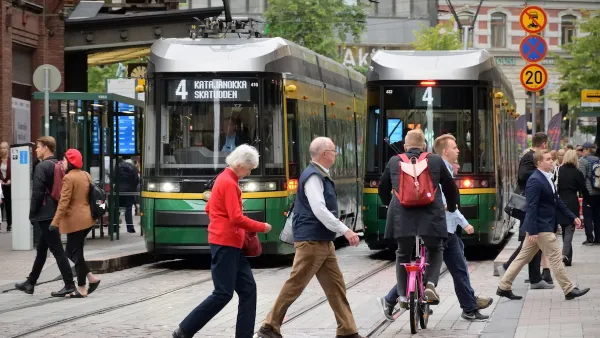 Busy Helsinki street with pedestrians and green streetcars.