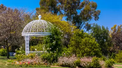 White gazebo among green plants and trees at botanical garden