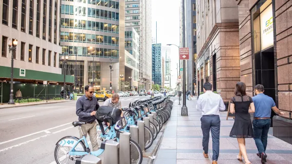 Divvy bike share station in Chicago with people checking out blue bikes.
