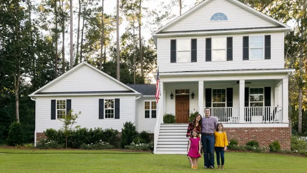 Family with woman, man, and two kids standing in front of white two-story traditional US home.