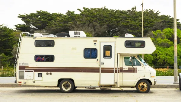 Small recreational vehicle parked on city street.