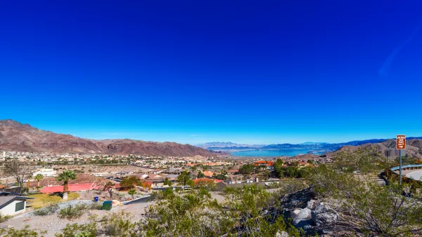 View of the mountain landscape near Boulder, Nevada. A town filled with houses with orange roofs is surrounded by mountains.