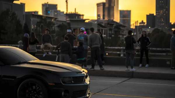 People standing at railing of Jackson Street Bridge in Atlanta at sunset overlooking downtown skyline.