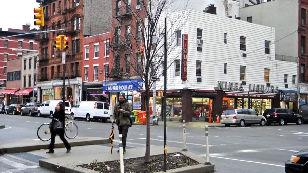 New York City intersection with red and white brick buildings and pedestrians.