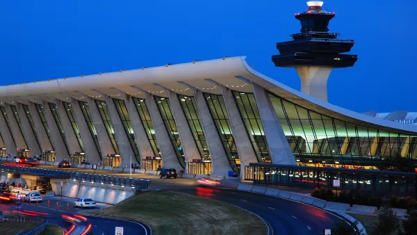 Terminal at Dulles Airport with control tower behind it at dusk.
