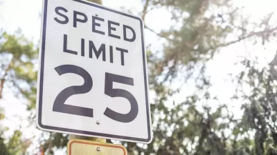 Black and white 25 mph speed limit sign on post with trees in background