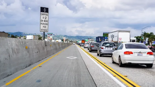 Empty carpool lane separated by yellow and black lines next to traffic on freeway in Southern California.
