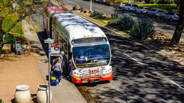 San Diego bus picking up passengers at a stop on a sunny day.