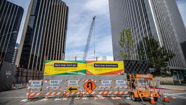 Street closure signs in front of construction wall and banner touting LA Metro's subway extension in front of high-rise buildings.