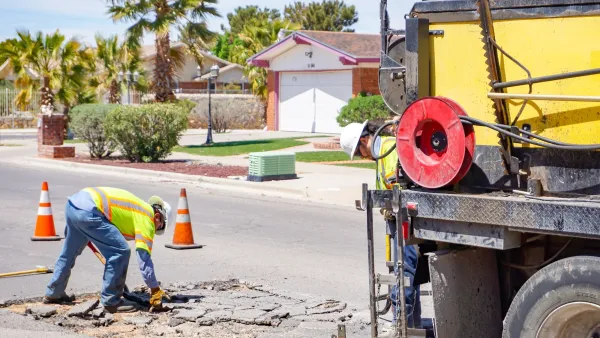 Worker in jeans and yellow safety vest repairing pothole on street in El Paso, Texas.