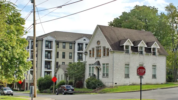 Tan brick two-story historic house next to four-story modern apartments with balconies on small street with tall trees in Nashville, Tennessee.