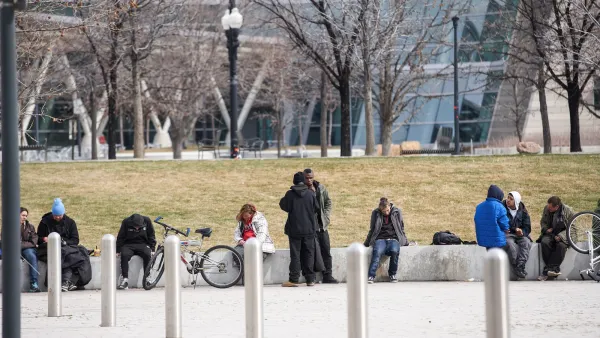 Unhoused people sitting on a concrete ledge in a public park in Salt Lake City, Utah.