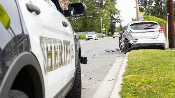 Close-up on Sheriff car parked next to grassy curb with silver car with damaged bumper stopped on grass immediately after crash.