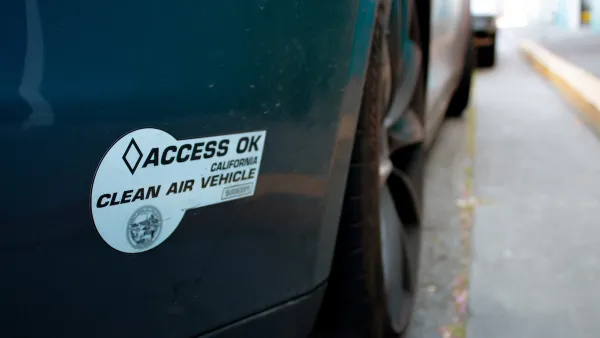 Close-up on "Access Ok" electric car sticker on back of dark colored car bumper.
