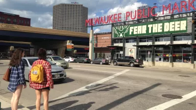 Two women waiting to cross street facing Milwaukee Public Market sign