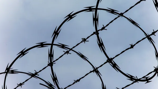 Close-up of razor wire at top of fence against blue sky.