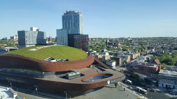Aerial of Barclays Center stadium in New York Coty with green roof and modern towers behind it.