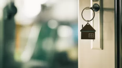 Close-up of key in door lock with house-shaped keychain hanging from it