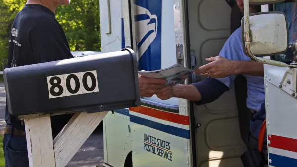 Close-up on postal worker hanging mail out of a mail truck to resident standing in front of black mailbox.