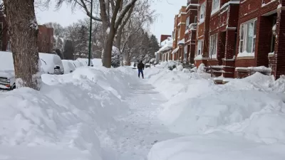 Snow-covered Chicago sidewalk with piles of snow on either side and red brick homes on the right