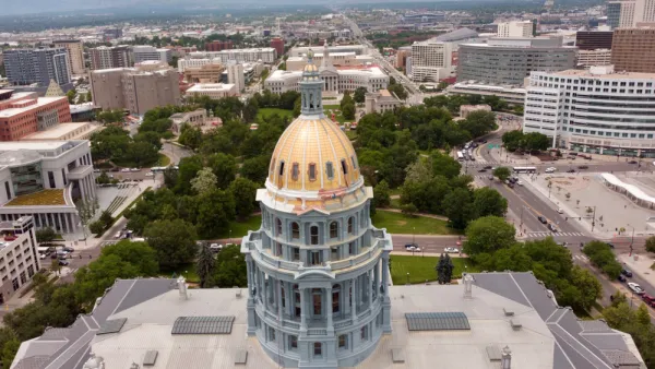 Aerial view of gold Colorado state capitol building with green park and city beyond 