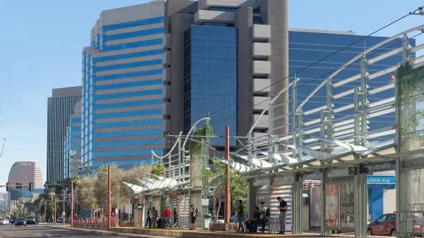 People waiting at a Phoenix light rail station under decorative shade elements.