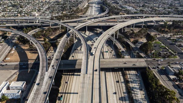 Aerial of ramps, bridges and traffic on the Harbor 110 and Century 105 freeway interchange in Los Angeles. The main road splits off in opposite directions midway through the photo. 
