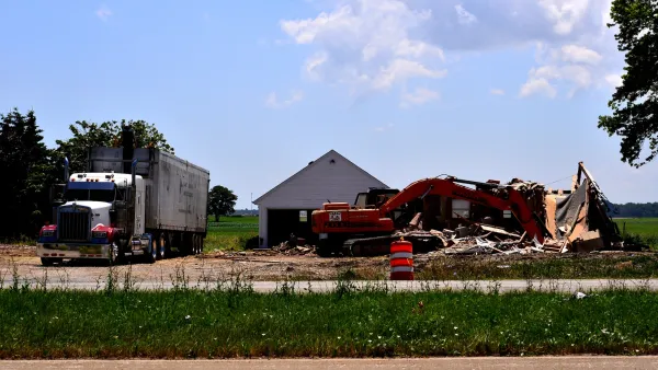 Small house in emmpty green frield being demolished to make way for road construction.