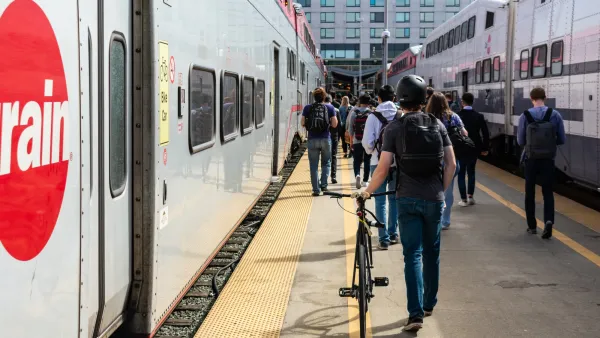 People walking bikes on Caltrain platform next to Caltrain bike car.