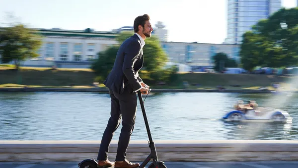 A businessman rides an e-scooter