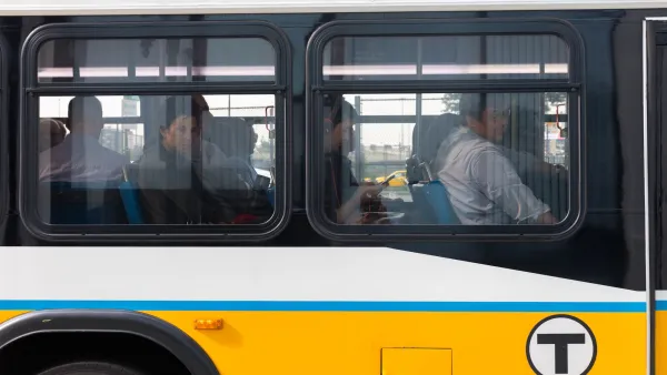 Close-up on MBTA bus window with passengers looking out from seats in Boston, MA.