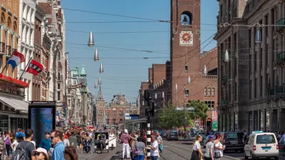 Crowded Amsterdam street with pedestrians, cars, and church in background