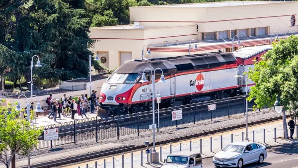 A Caltrain train picks up a large crowd of people at a station.