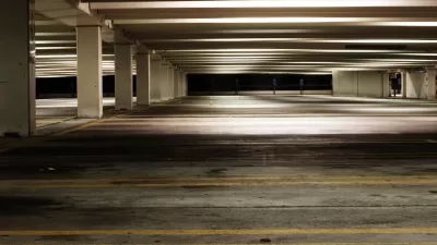 Empty parking garage at night with yellow lines marking spots and fluorescent lighting
