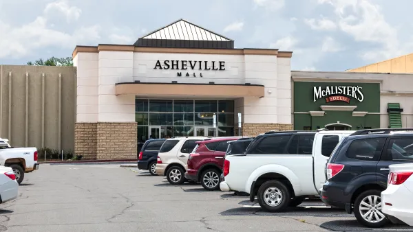 The main front entrance to the Asheville Mall, showing parking lot and cars.