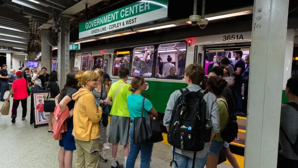 A crowd of people boarding Boston's green line in an underground subway station.
