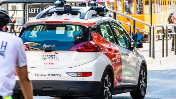 Self-driving white and red Cruise vehicle (Chevy Bolt body) in San Francisco with cyclist following behind