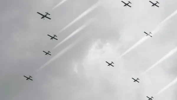 Against a cloudy sky, a group of planes cloud seed by spraying salt into the clouds.