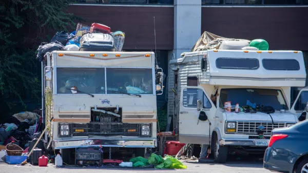 Two RVs used as homes by their residents surrounded by household items in parking lot in North Hollywood, California.