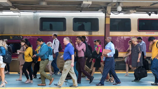 A group of people walk past Boston's purple commuter rail.