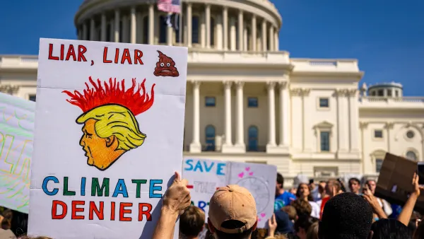 Protesters holding up anti-Trump climate protest signs in front of Capitol dome in Washington DC. 