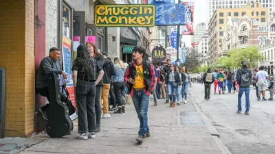 Austin's Sixth Street full of pedestrians during SXSW festival with yellow sign for Chuggin Monkey bar in foreground