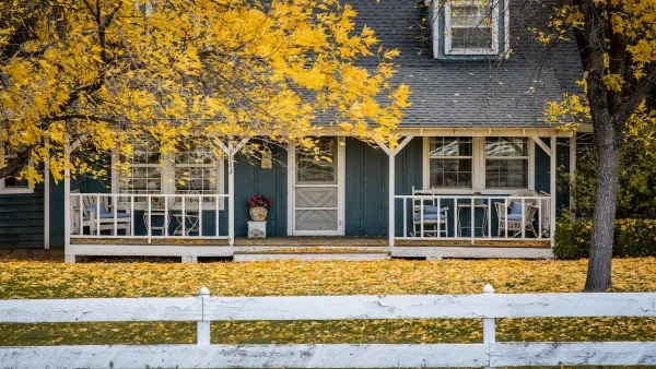 Grey traditional two-story house in Meridian, Idaho with trees with yellow fall leaves in front.