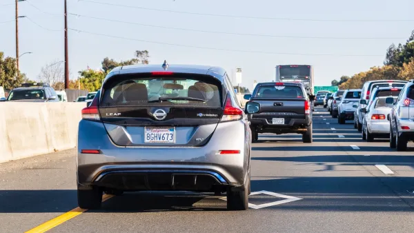 Silver sedan in carpool lane on California freeway on sunny day.
